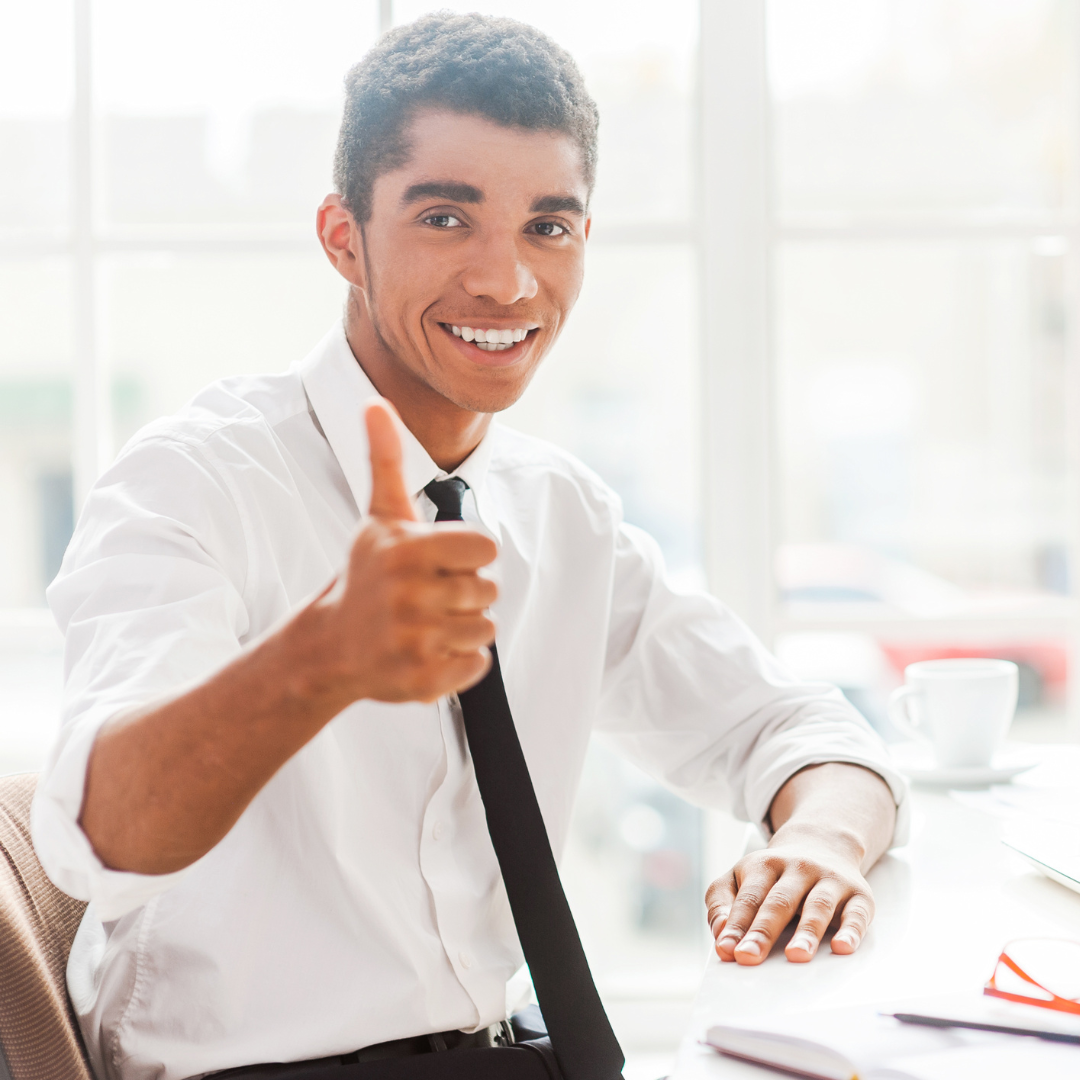 Man sitting at a desk with thumbs up